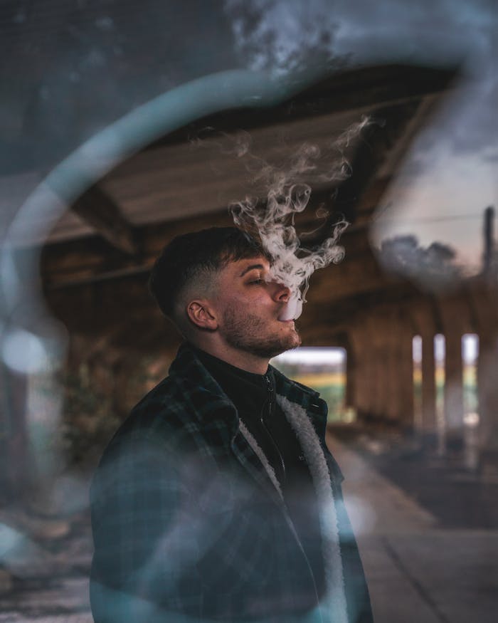 pexels-photo-3535034 A stylish young man exhales vape smoke in an atmospheric abandoned building.