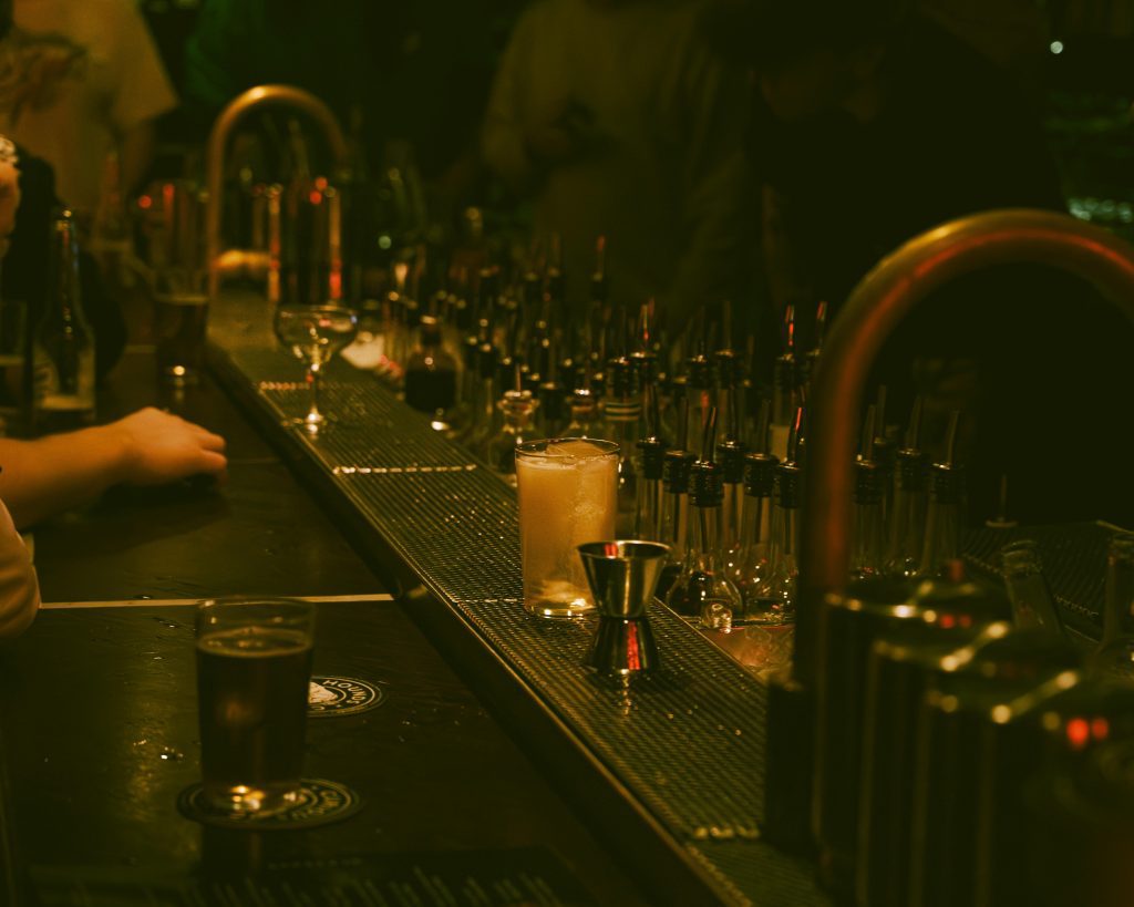 pexels photo 36107885 36107885 A dimly lit bar with a drink and bar tools creating a moody atmosphere.