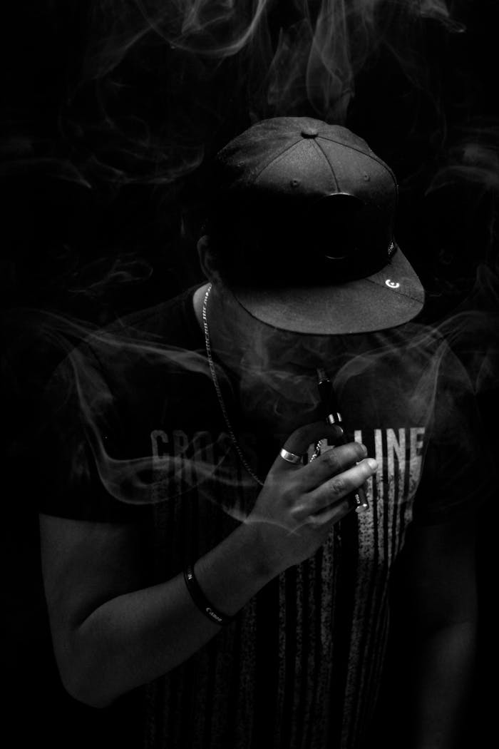 our-experience Striking black and white portrait of a person vaping surrounded by smoke.